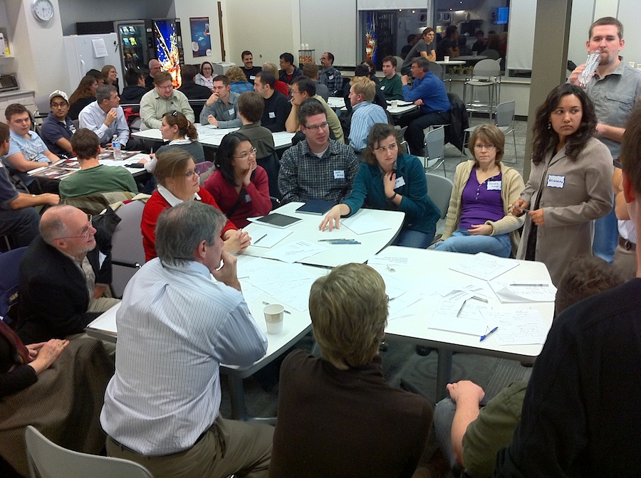 Groups of people at tables working on a design exercise