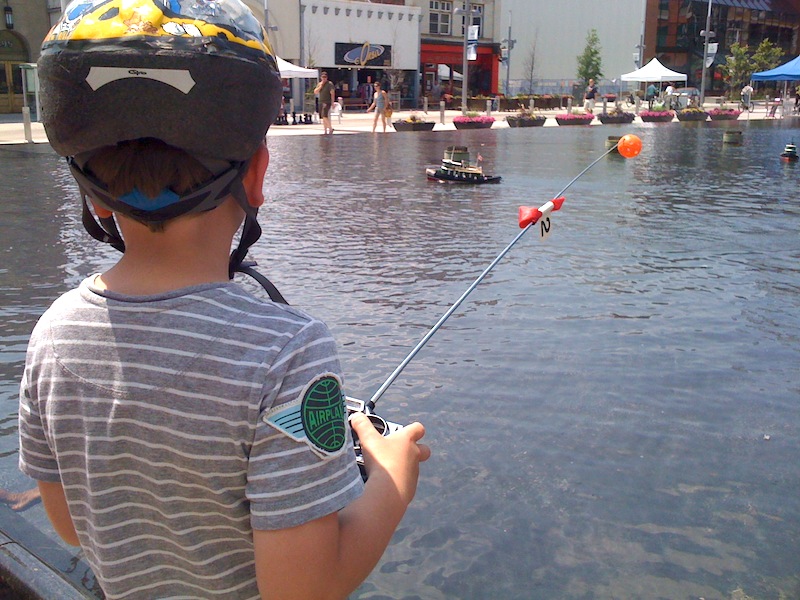 A child remotely controls a model boat