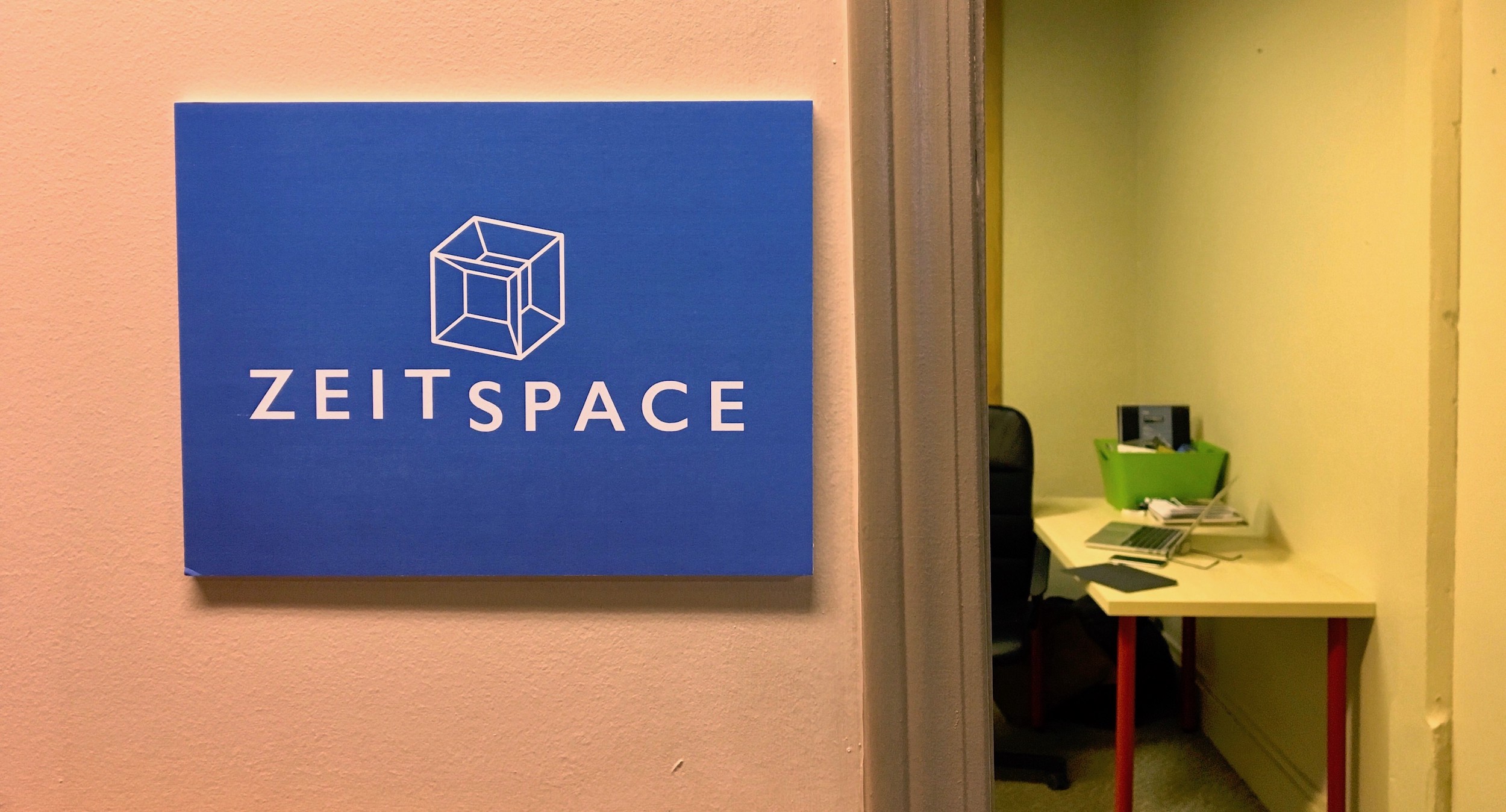 A Zeitspace sign on a wall next to an open door