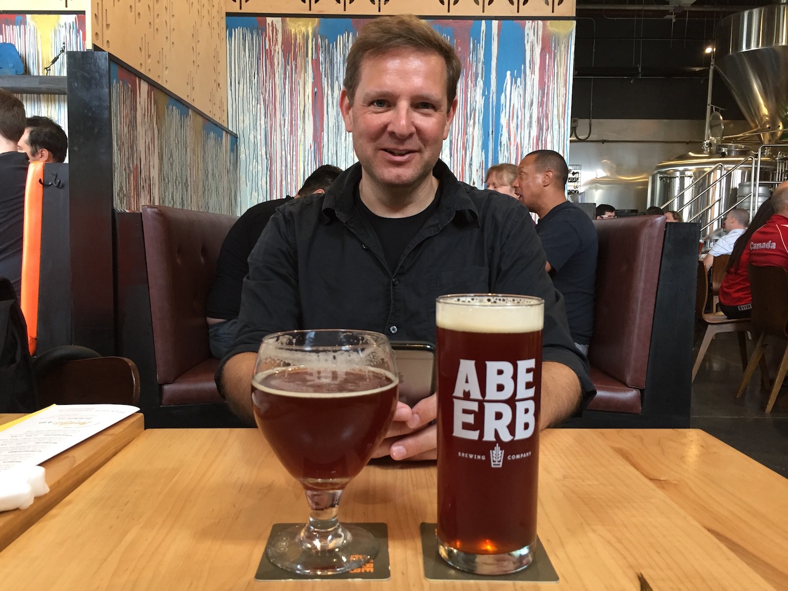 A person looking at the camera over glasses of beer