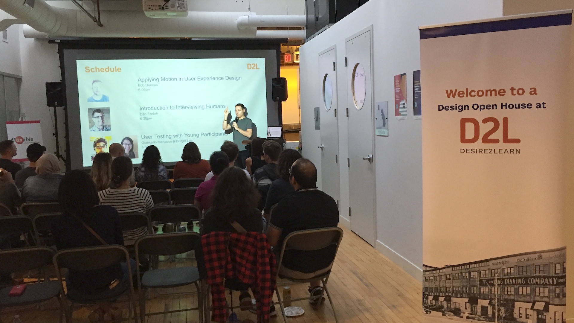 A person standing in front of a screen, presenting to a group seated in chairs