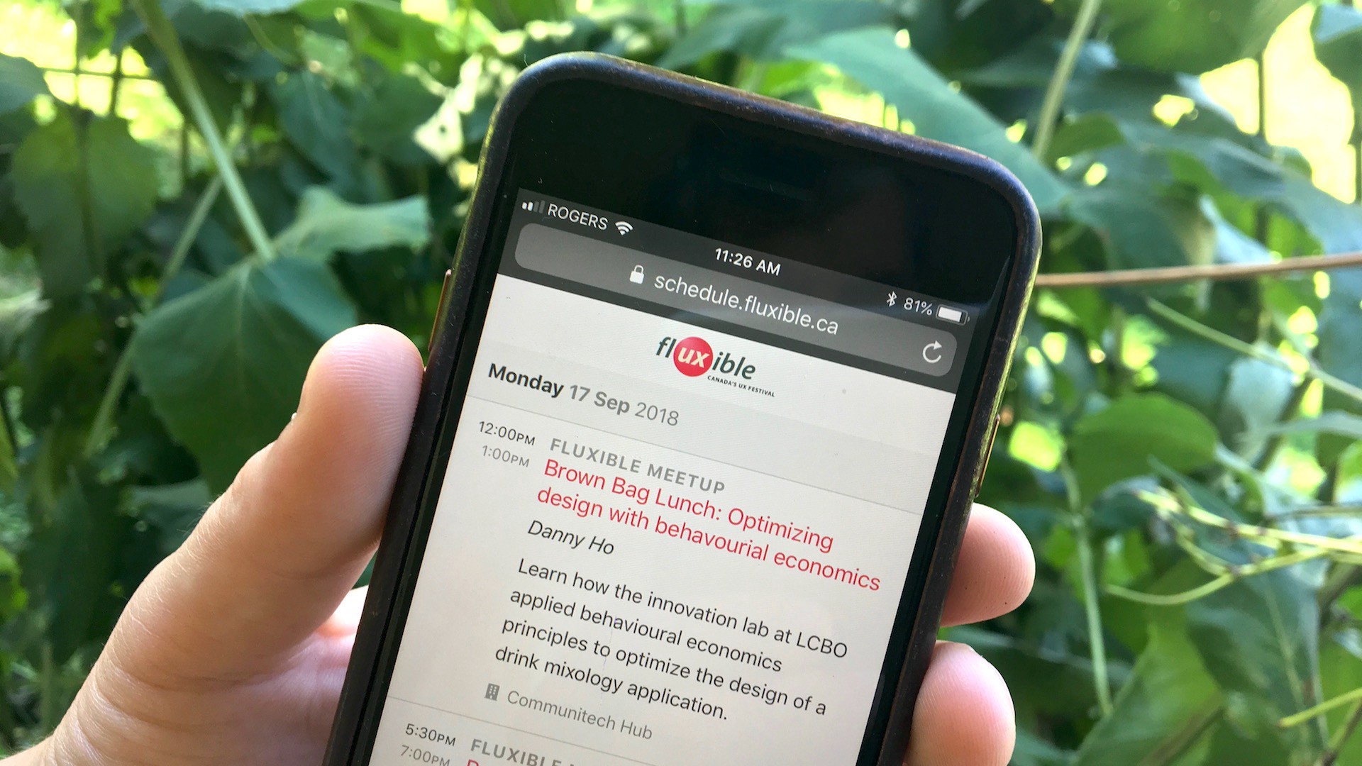 A hand holding a mobile phone that shows a schedule for Fluxible
